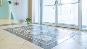 A lobby with a patterned rug, a fire alarm, and a potted plant. - 213 Beachfront Heated Pool Gulf View Studio (Galveston)