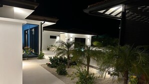 A modern house with a well-lit outdoor area, including a pathway and various plants. - Villa Gouverneur, Tamarindo, hacienda Pinilla, Avellanas, Langosta, Costa Rica (Tamarindo)