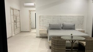 A bedroom with a bed, nightstands, a small table, and wicker furniture. - Villa Gouverneur, Tamarindo, hacienda Pinilla, Avellanas, Langosta, Costa Rica (Tamarindo)