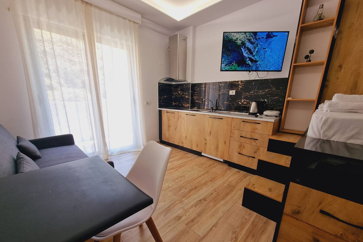 A modern kitchen with wooden cabinets, a black countertop, and a built-in TV.