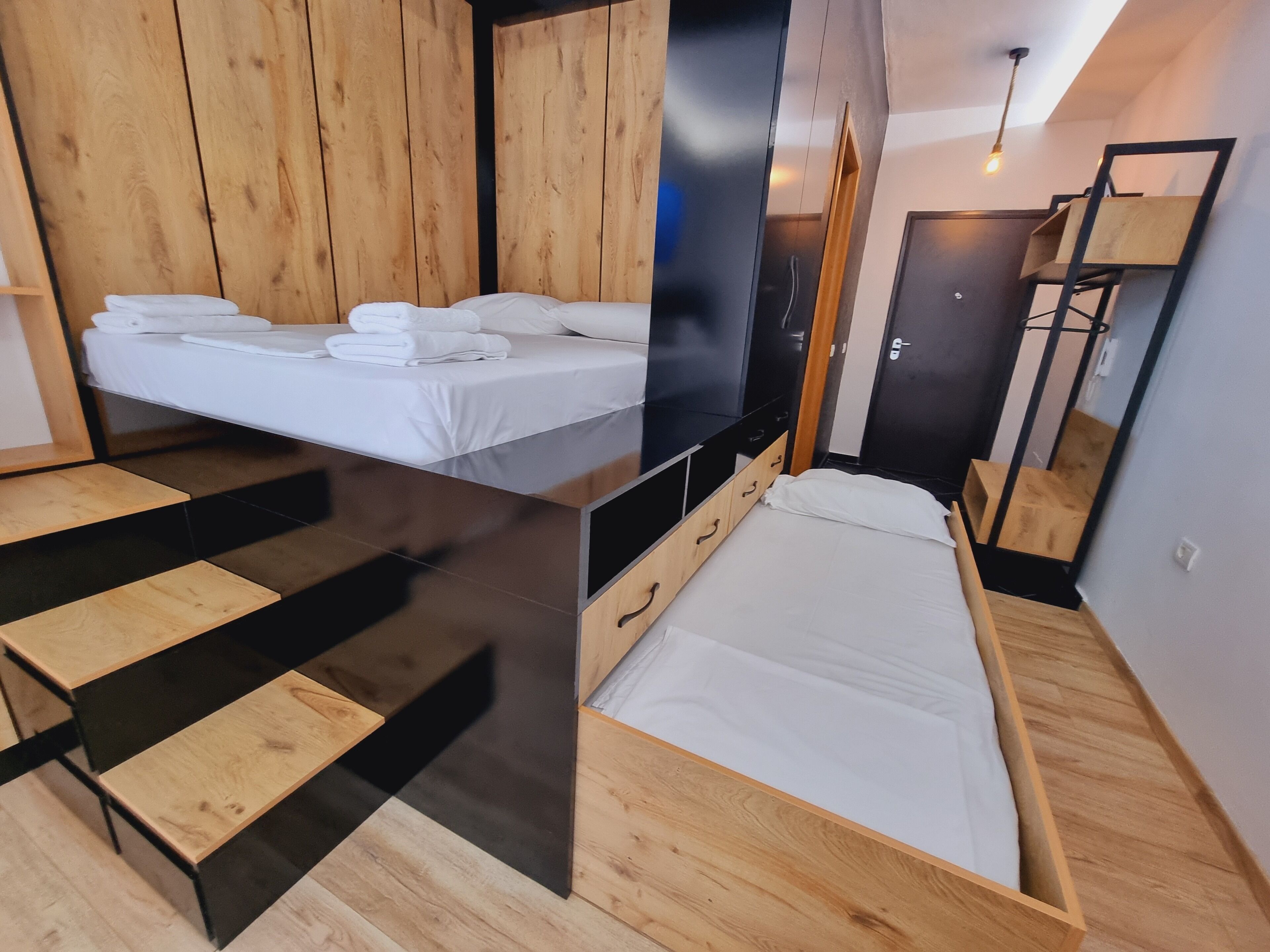 A modern bedroom with a bed, a desk, and a wardrobe.