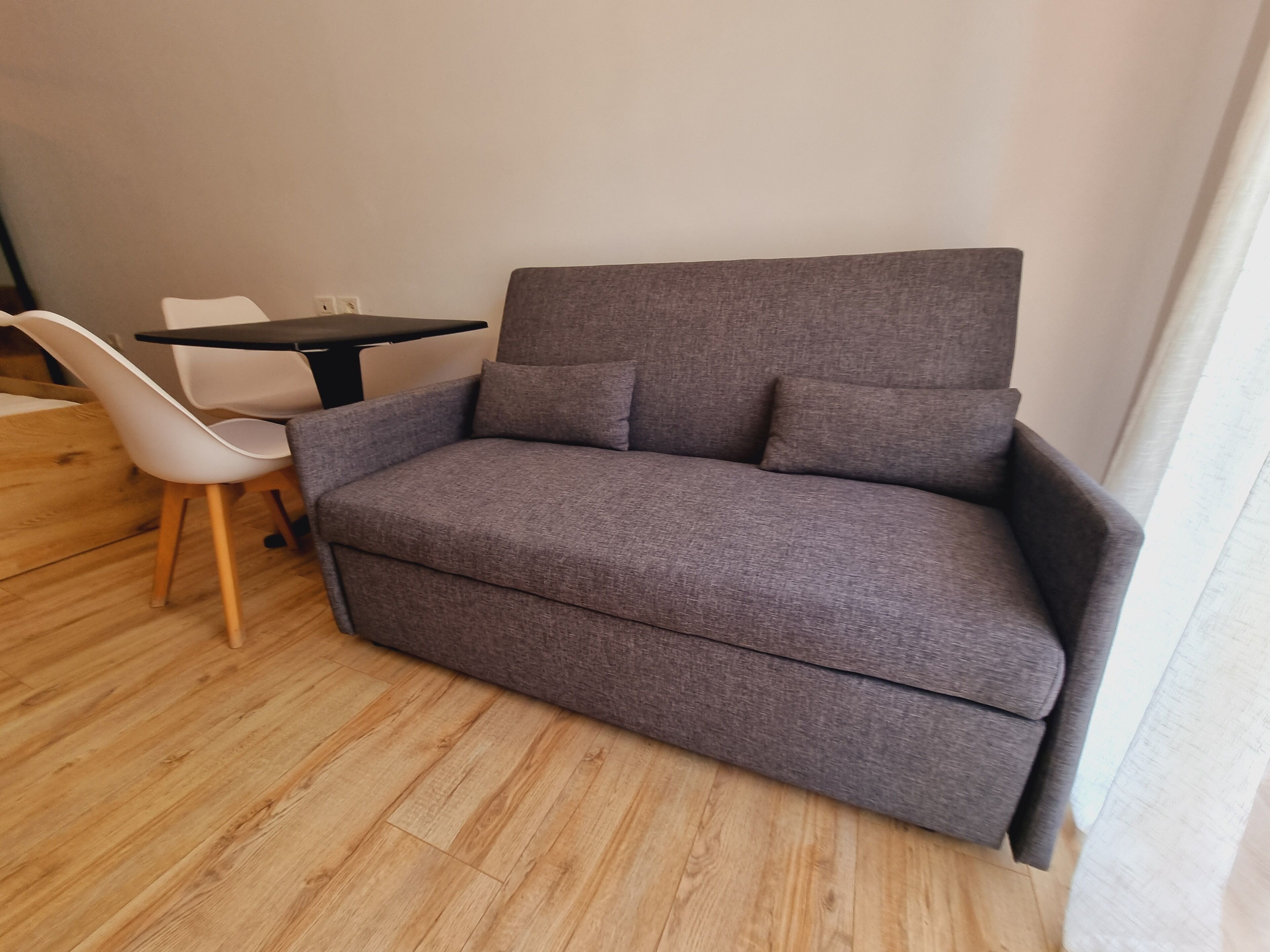 A modern room with a grey sofa, a white chair, and a small table.