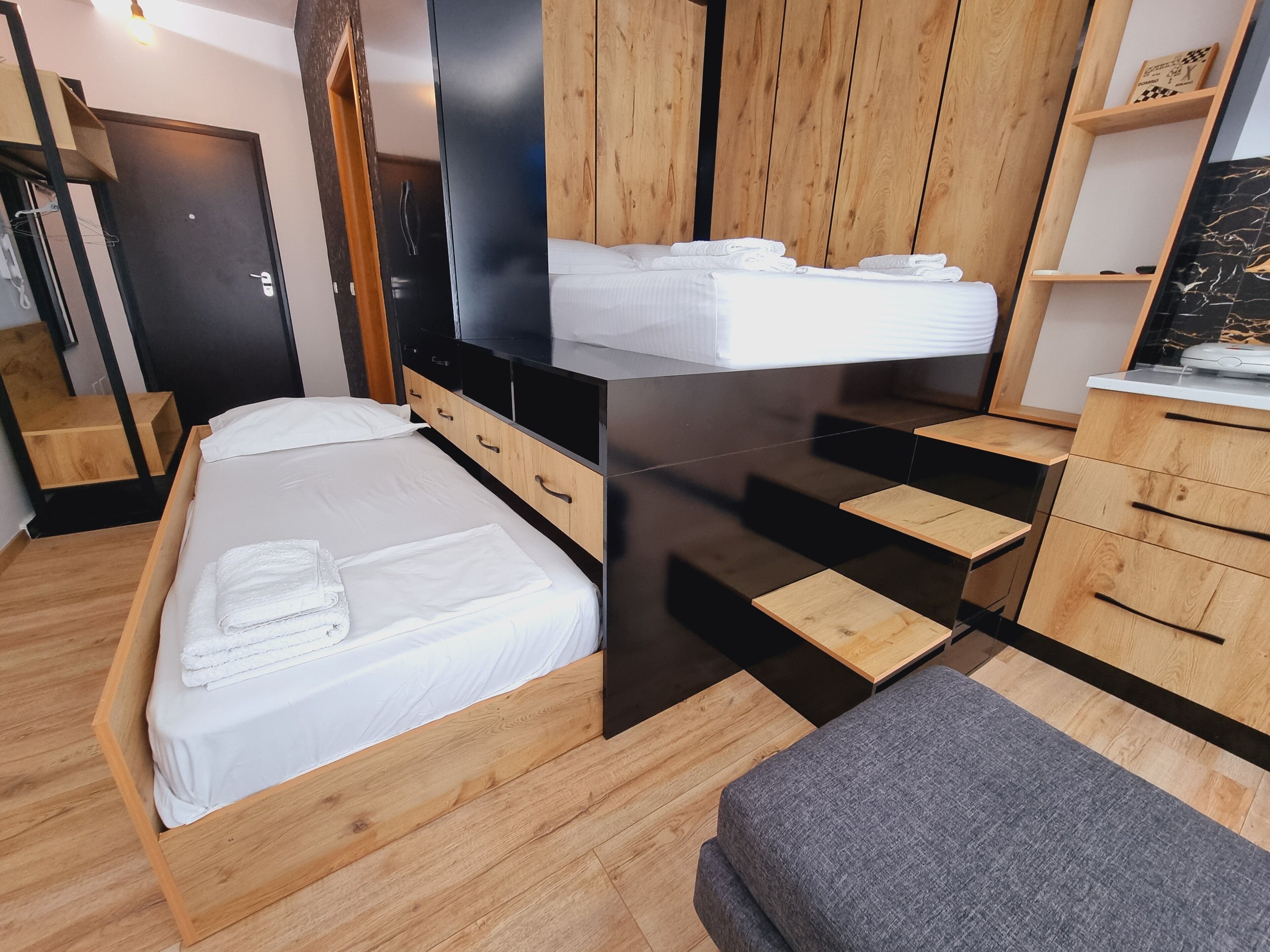 A modern bedroom with a bed, wooden drawers, a TV, and a wooden wardrobe.