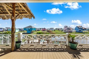 A wooden deck with a thatched roof, white railing, and potted plants. - New Listing 4BR/3Bath TikiBar Canal View Game Room (Bolivar Peninsula)