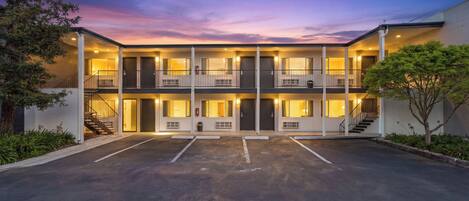 Un motel de varios pisos con un patio central, balcones y un estacionamiento.