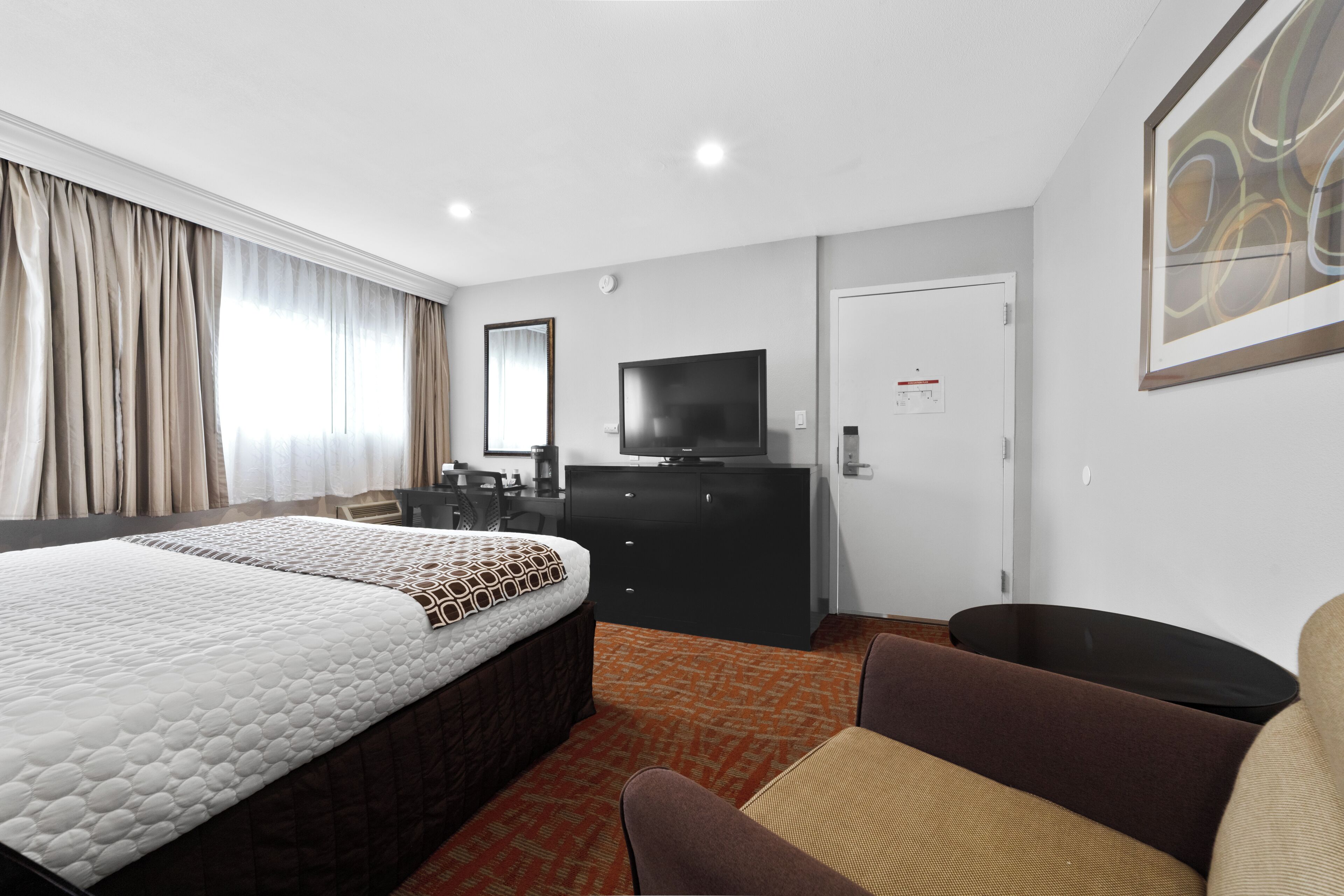 Habitación de hotel con una cama grande, un escritorio, un televisor y un cuadro en la pared.