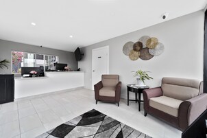 Una sala de estar moderna con un sofá, sillones, una mesa de centro y un adorno en la pared.