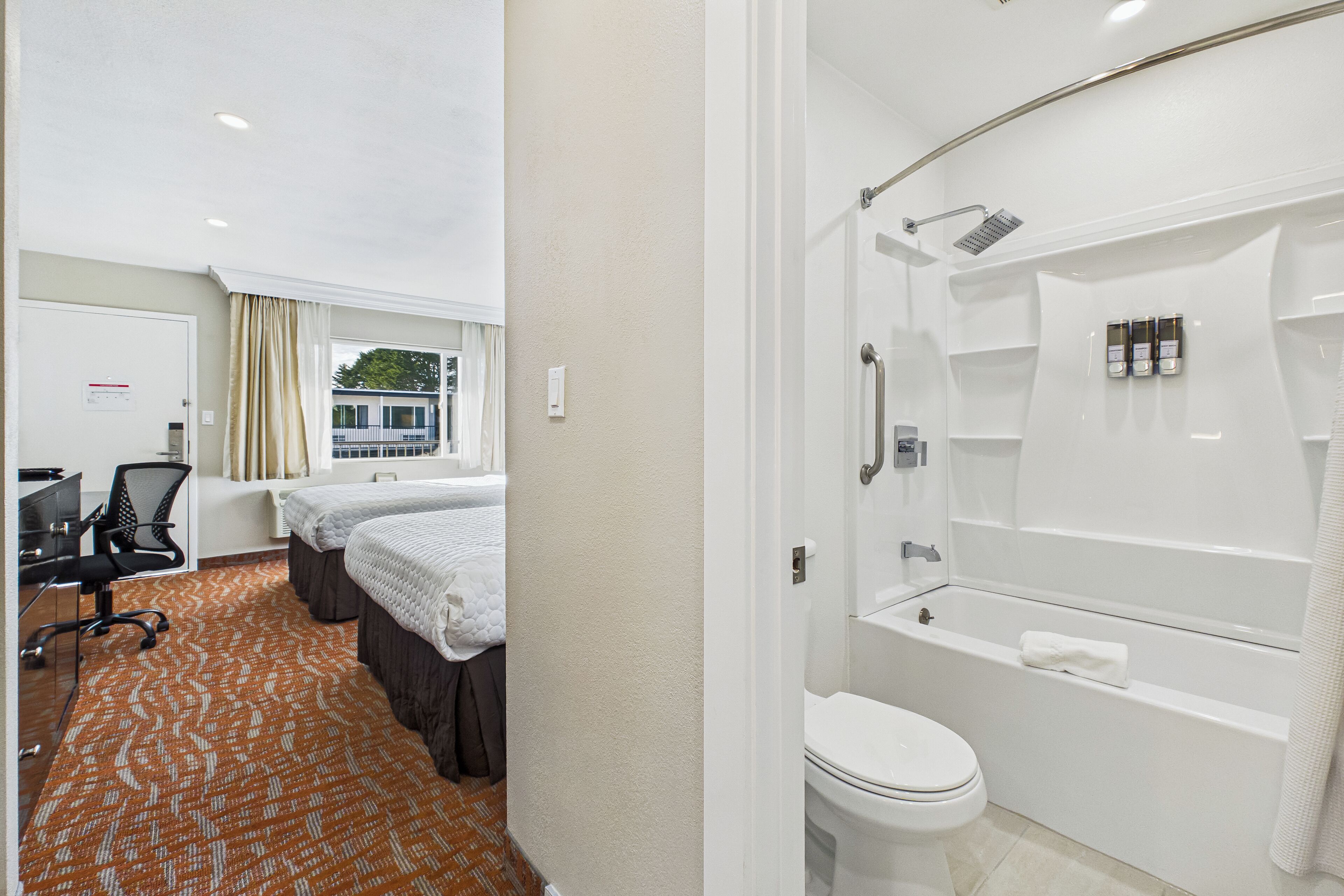 Une chambre d’hôtel équipée d’une douche, de toilettes et d’un bureau avec une chaise.