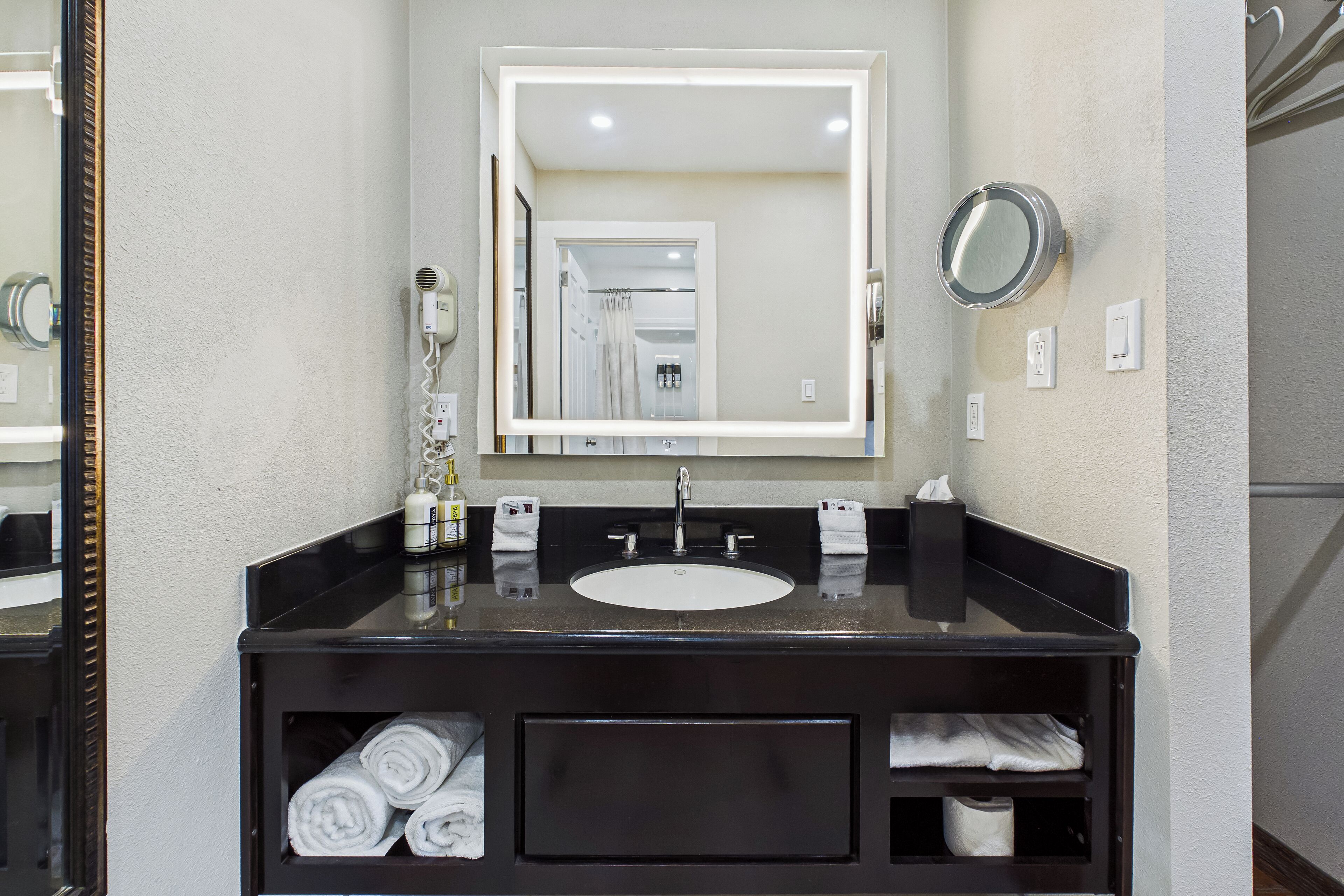A bathroom with a large mirror, a sink, and a towel rack.