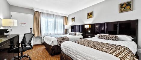 Habitación de hotel con dos camas, un escritorio y una silla.