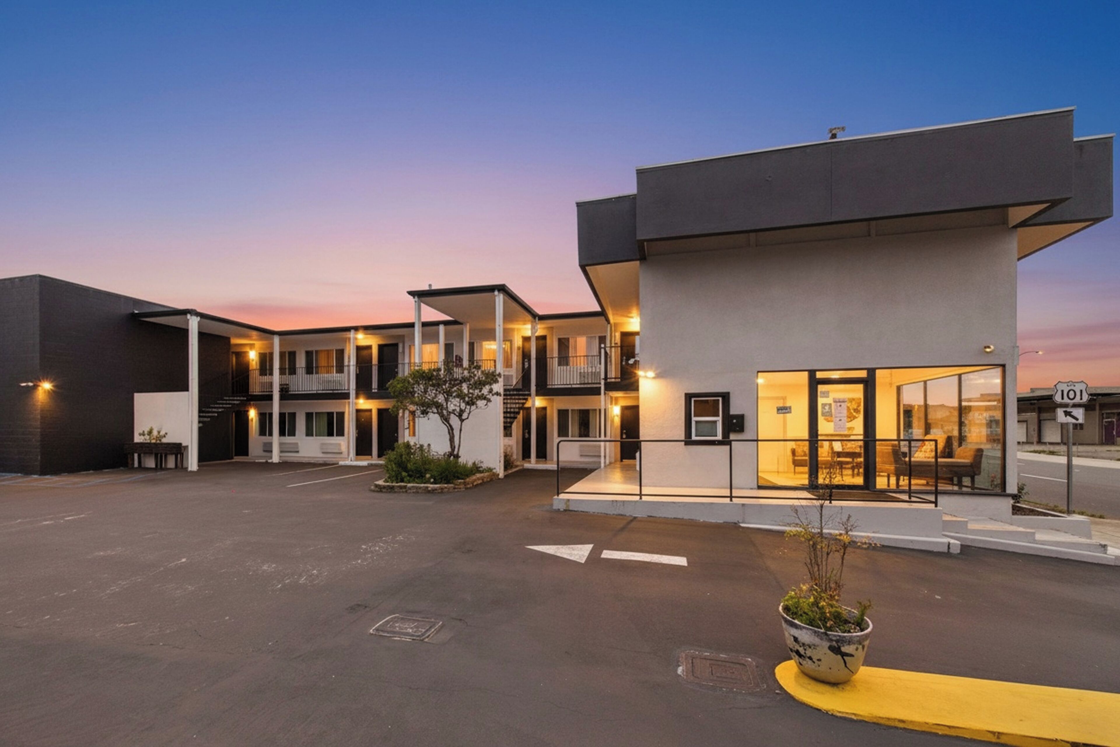 A modern building with a flat roof, large windows, and a covered entrance area.