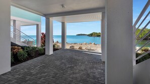 Un espacio al aire libre cubierto con vistas al mar, que cuenta con suelo de baldosas y barandillas blancas.