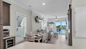 Una cocina moderna con horno empotrado, comedor con sillas y mesa, y vista a una piscina a través de un ventanal.