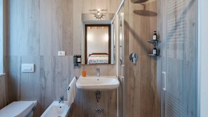 Une salle de bain moderne avec un mur recouvert de panneaux en bois, un lavabo avec un miroir au-dessus, une douche avec un pommeau de douche à main et des toilettes.