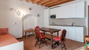 Une cuisine de taille réduite avec des meubles blancs, une table à manger en bois et des chaises rouges.
