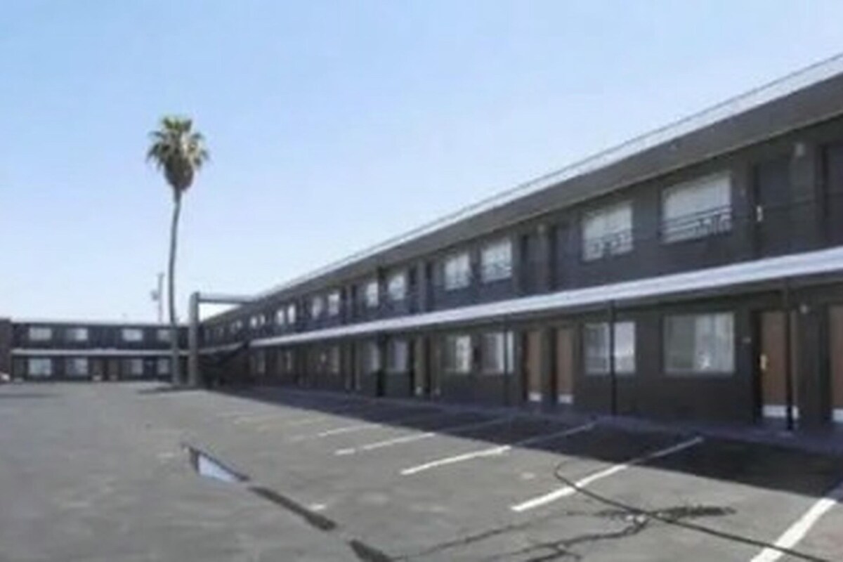 A modern building with a flat roof and a parking lot in front.