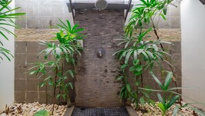 Un espacio reducido y cerrado con piso de baldosas, pared de ladrillo y puerta metálica.