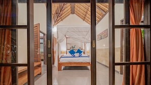 Un dormitorio con cama, dosel y un banco de madera.