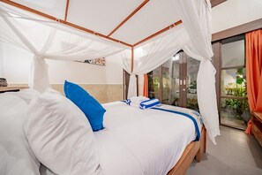 Ein Schlafzimmer mit Himmelsbett, Blick ins Freie und einem kleinen Tisch mit einem dekorativen Gegenstand.