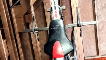 A Bowflex XtremE home gym setup with a red mat, metal frame, and black seat.