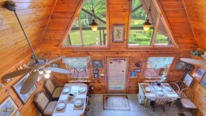 Una cabaña de madera acogedora con dos zonas de comedor, cada una con una mesa dispuesta para cuatro personas.