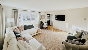Un salon spacieux comprenant un grand canapé, un canapé plus petit, une table basse et un téléviseur fixé au mur.