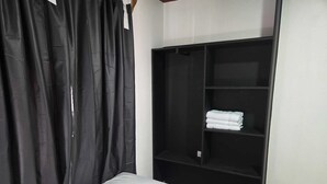 Una habitación con cama, armario negro y cortina.