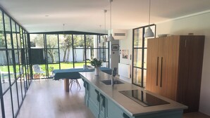 Une cuisine moderne dotée de grandes fenêtres, d’un îlot central et offrant une vue sur le jardin.