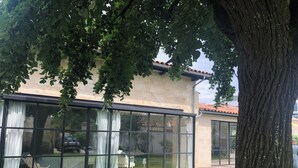 Une maison moderne dotée de grandes baies vitrées, d’une terrasse en bois et d’une pelouse bien entretenue.