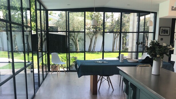 Une cuisine spacieuse avec de grandes fenêtres, une table à manger et une vue sur le jardin arrière.