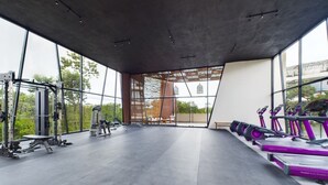 A gym with treadmills, weight machines, and a large window overlooking greenery.