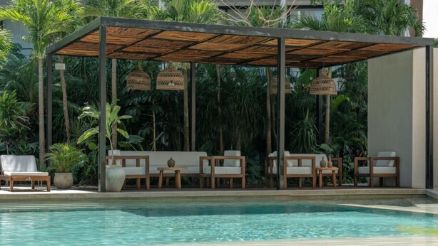 A poolside area with lounge chairs and a covered seating area.