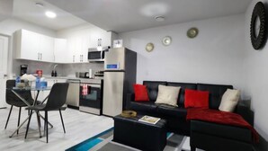 A modern kitchen with white cabinets, a black countertop, and a dining area with a glass table and black chairs.