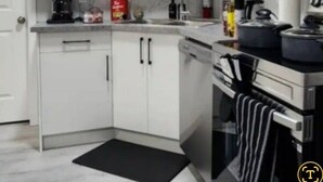 A modern kitchen with white cabinets, a built-in oven, and a microwave.