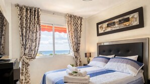 A bedroom with a bed, curtains, a bedside table, a lamp, and a ceiling light. - Beachfront Escape with Spacious Terrace and Stunning Seaview (Torrevieja)