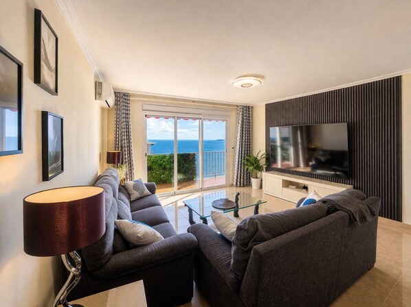 A modern living room with a sofa set, a TV, and a view of the sea. - Beachfront Escape with Spacious Terrace and Stunning Seaview (Torrevieja)