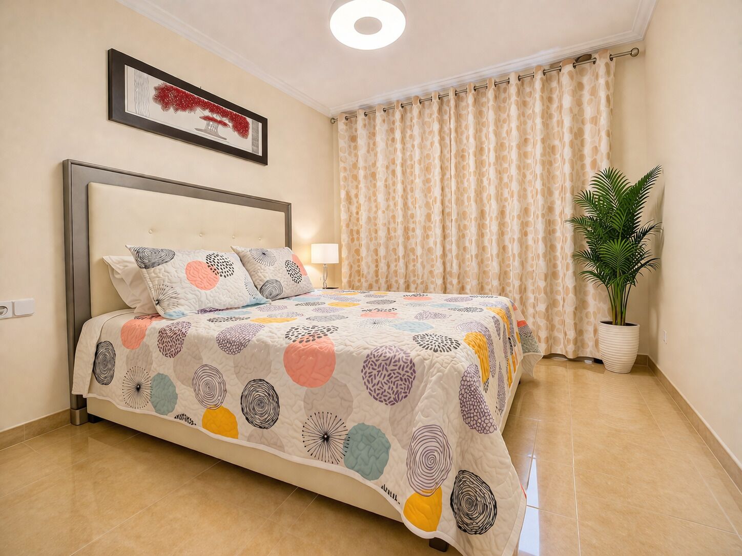 Un dormitorio ordenado con una cama, una planta en maceta y un ventanal con cortinas.