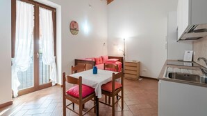A compact living space with a dining area, kitchenette, and a bedroom with a bed and a nightstand.
