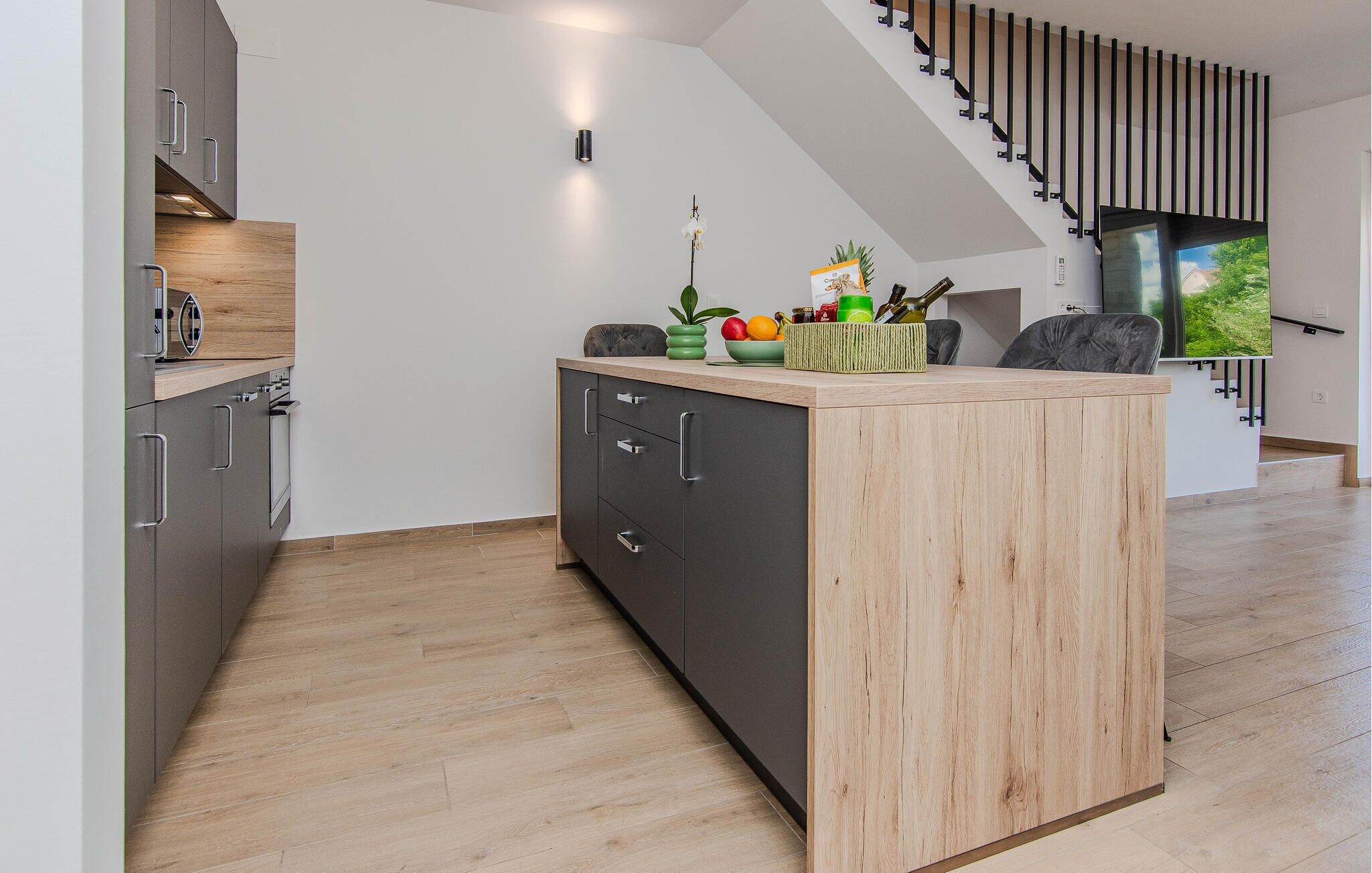 A modern kitchen with a central island, dark cabinetry, and a wooden countertop.