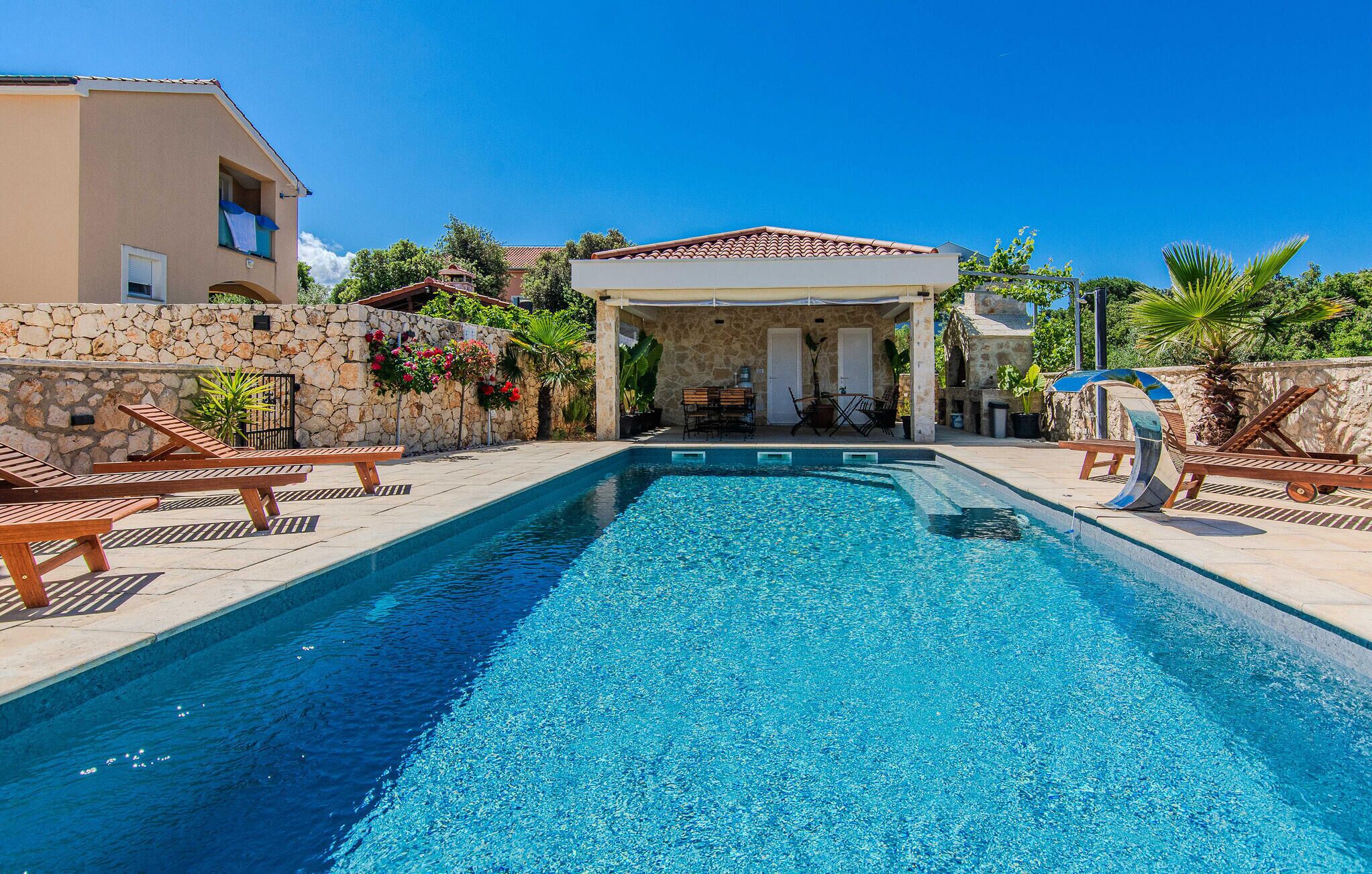 A swimming pool with lounge chairs and a covered seating area.