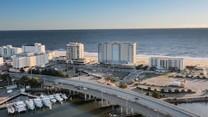 A coastal cityscape with high-rise buildings, a marina with boats, and a beach in the background. - Oceanfront Condo, Heated Pool, Fitness Center (Virginia Beach)