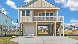 Ein zweigeschossiges Haus mit Balkon, Garage und einer überdachten Veranda.