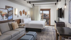 Una habitación de hotel con cama, sofá, televisión y obras de arte en las paredes.