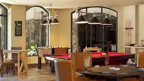 Un área de comedor con mesa de billar, sillas y alfombra roja.