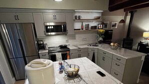 Una cucina moderna con isola in marmo, elettrodomestici in acciaio inox e travi a vista in legno.