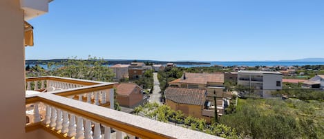 A balcony with a view of a residential area, featuring houses with red-tiled roofs and a clear blue sky.