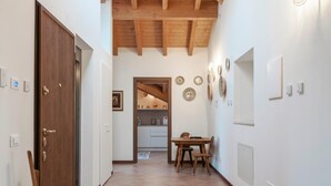 A hallway with a wooden door, a dining table with chairs, and a kitchen visible in the background. - 5) Spacious Apartment in Agriturismo with Two Terraces and Panoramic View (Pralboino)