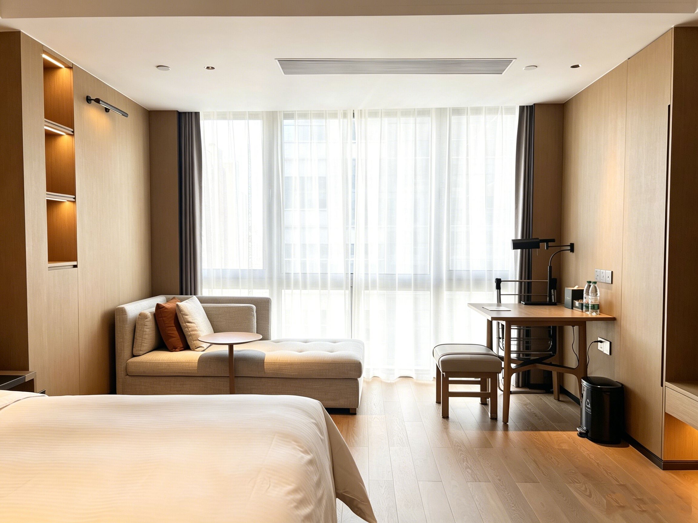 A hotel room with a bed, a sofa, a desk, and a chair.