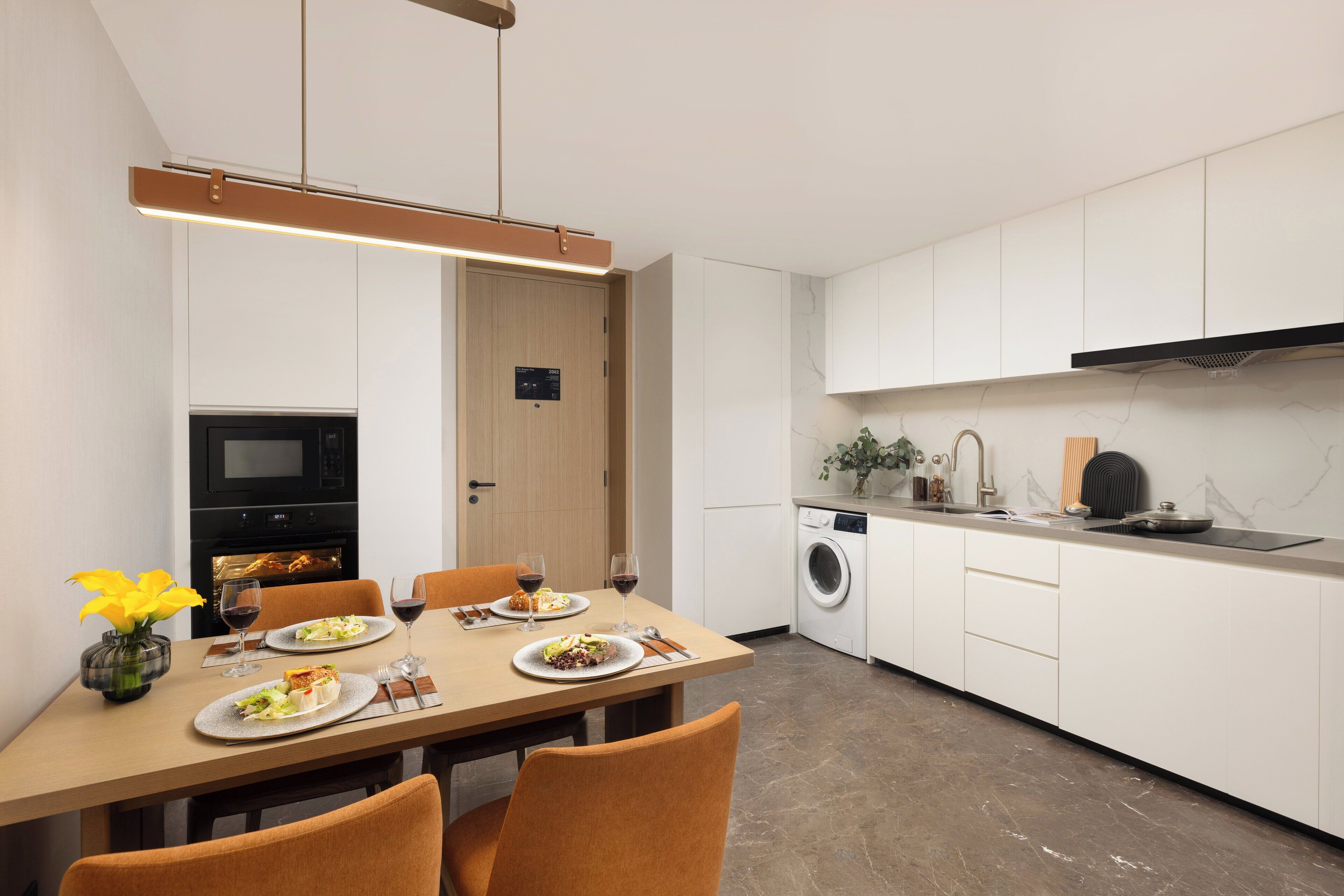 A modern kitchen with white cabinets, a built-in oven, and a washing machine.