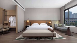 Une chambre d’hôtel moderne dotée d’un grand lit, d’un coin salon, d’une petite table et offrant une vue sur la ville.
